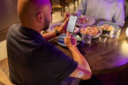 Chris out to eat and looking at readings on his phone while wearing the Dexcom sensor