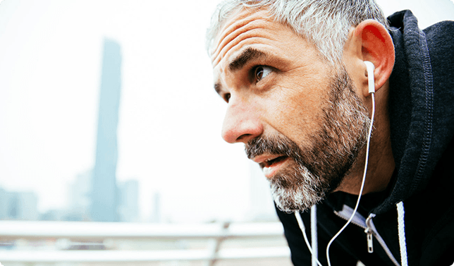 Man bending down wearing wired earbuds looking to the left