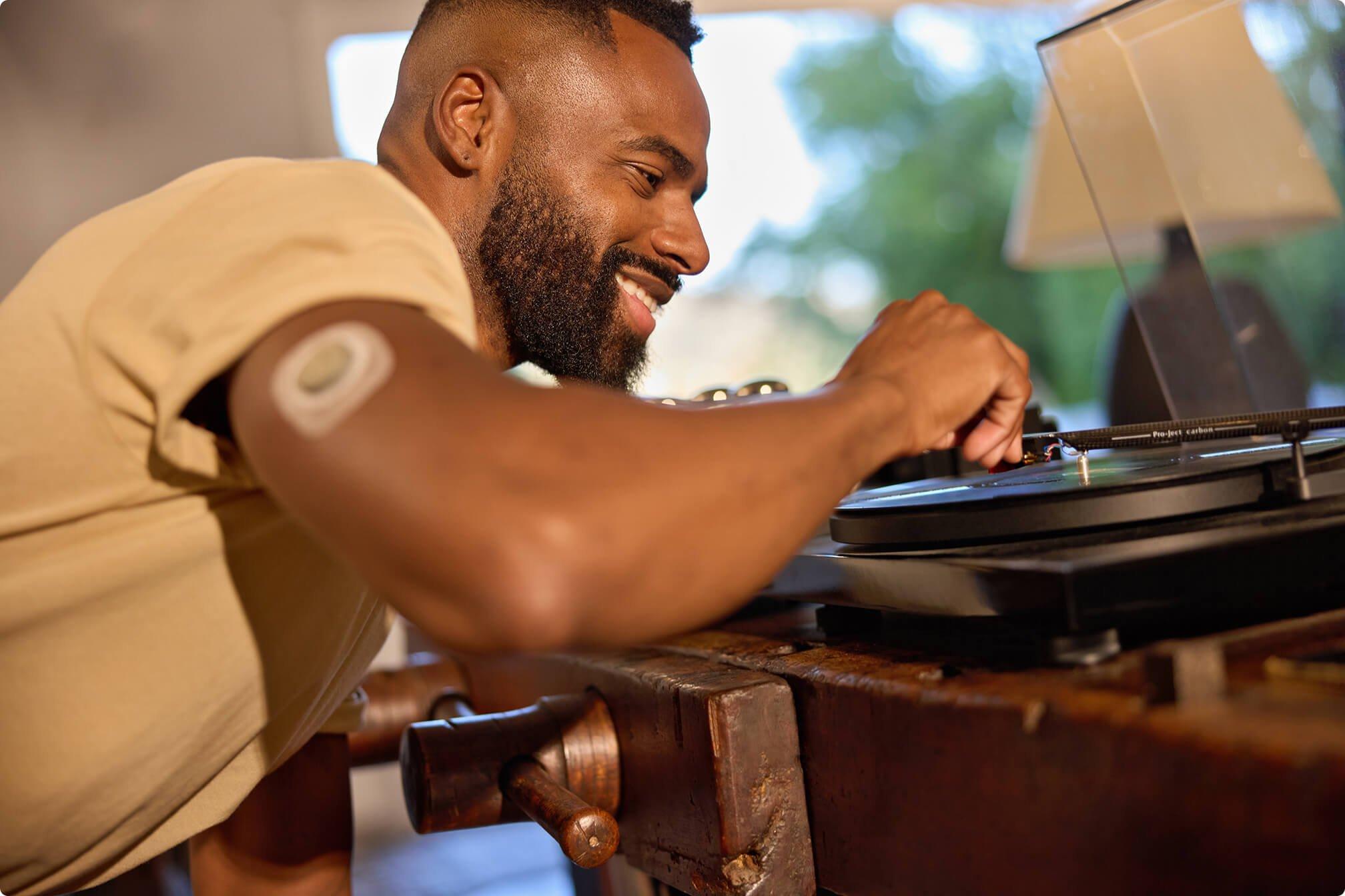 Man wearing Stelo sensor adjusting record player