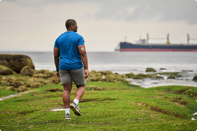 Man walking on a field next to water wearing Stelo sensor