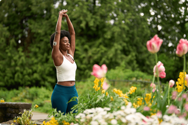 Woman doing yoga on a patio next to flowers while wearing Stelo sensor