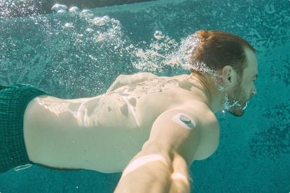 Man swimming underwater while wearing Stelo sensor