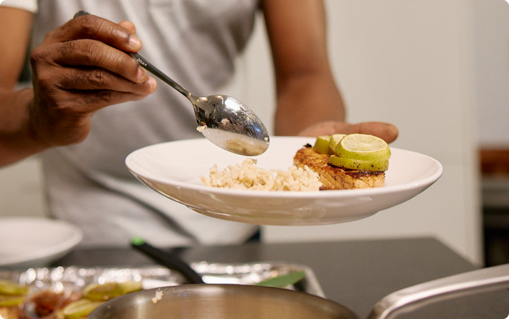 Person eating a meal with rice, fish and lime slices.