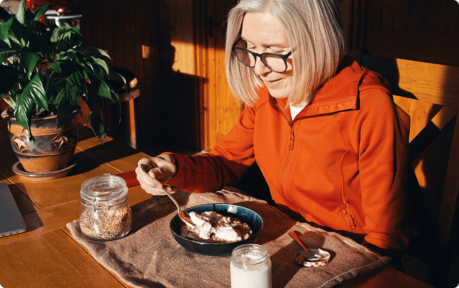 Woman sitting at a table in the sun eating breakfast