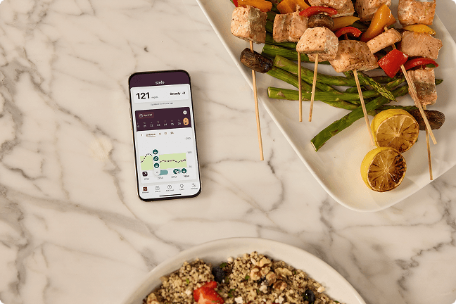 Phone showing readings on a table with plates of food next to it