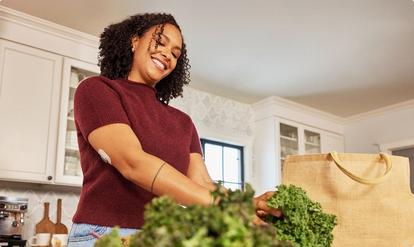 Woman wearing Stelo sensor unpacking greens from a bag
