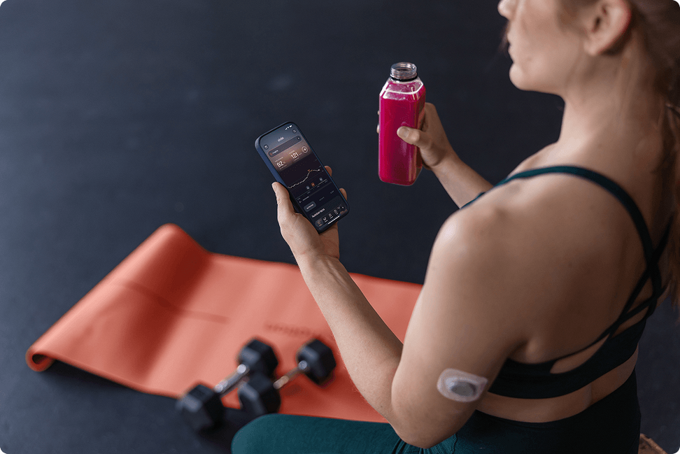 Woman wearing Stelo sensor checking her readings during a workout