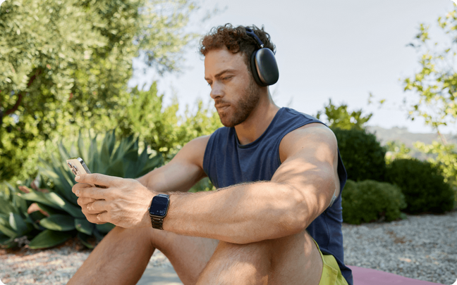 Man looking at his phone sitting down wearing headphones