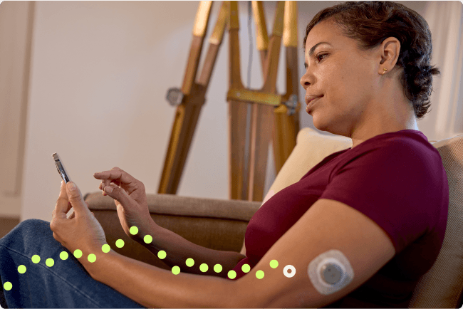 Woman sitting down on her phone while wearing the Stelo sensor