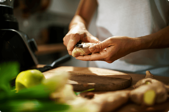 Person peeling  ginger over a cutting board
