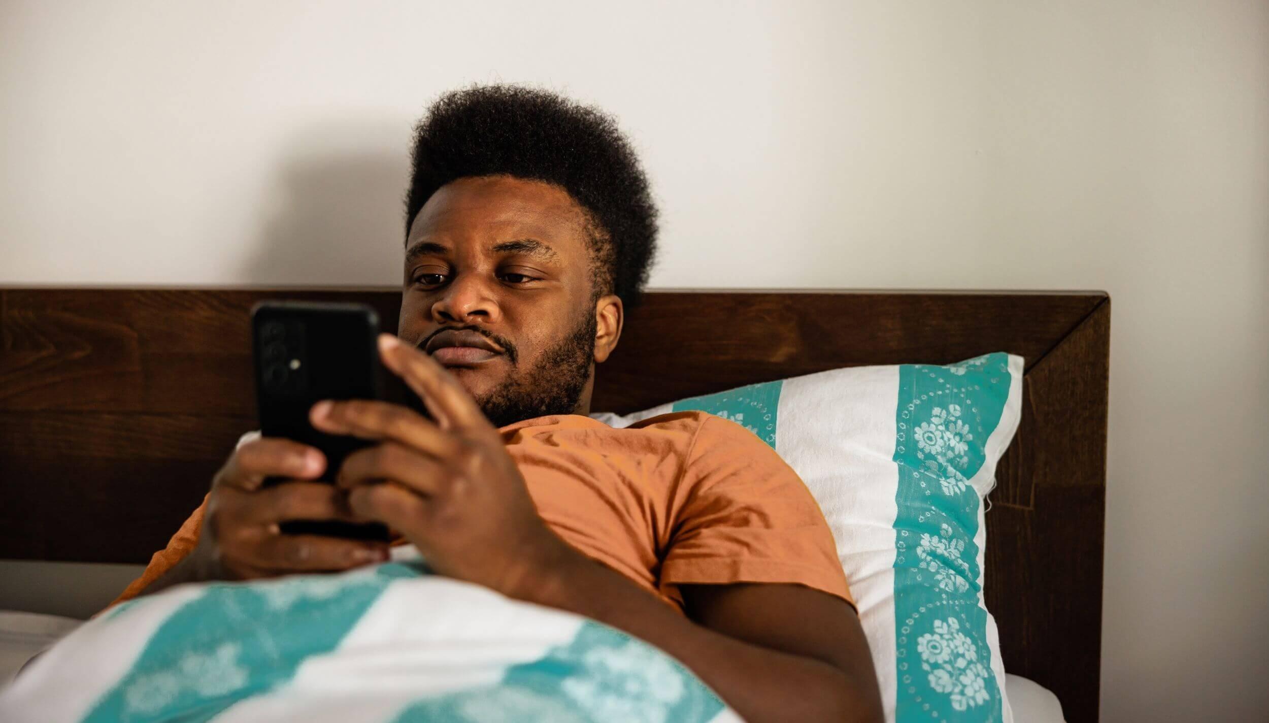 Man lying in bed on his phone