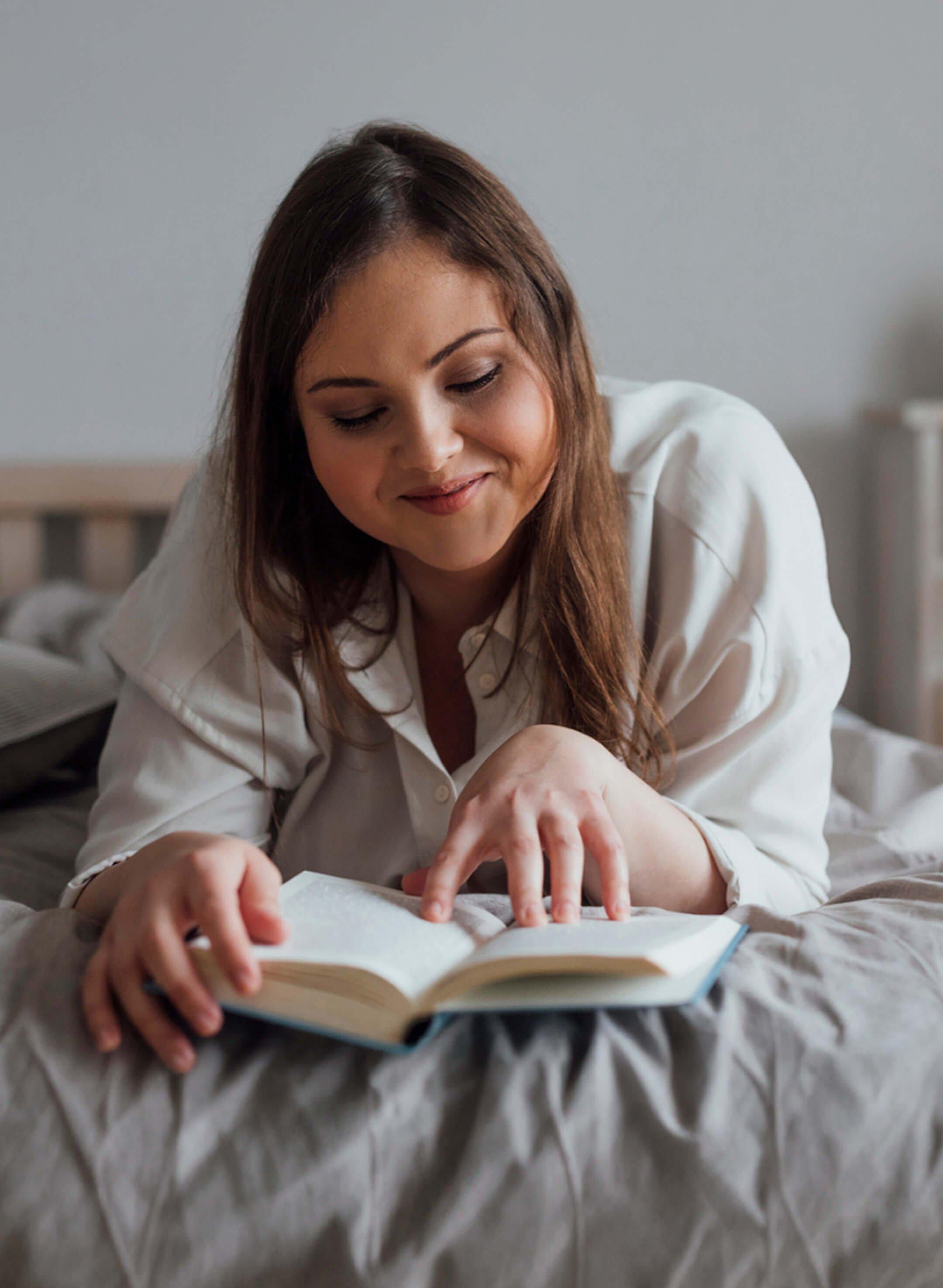 Woman laying down on her bed reading
