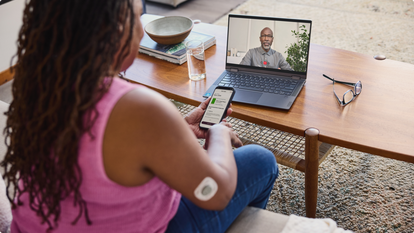 Woman talking with a man over video chat while looking at readings on phone.