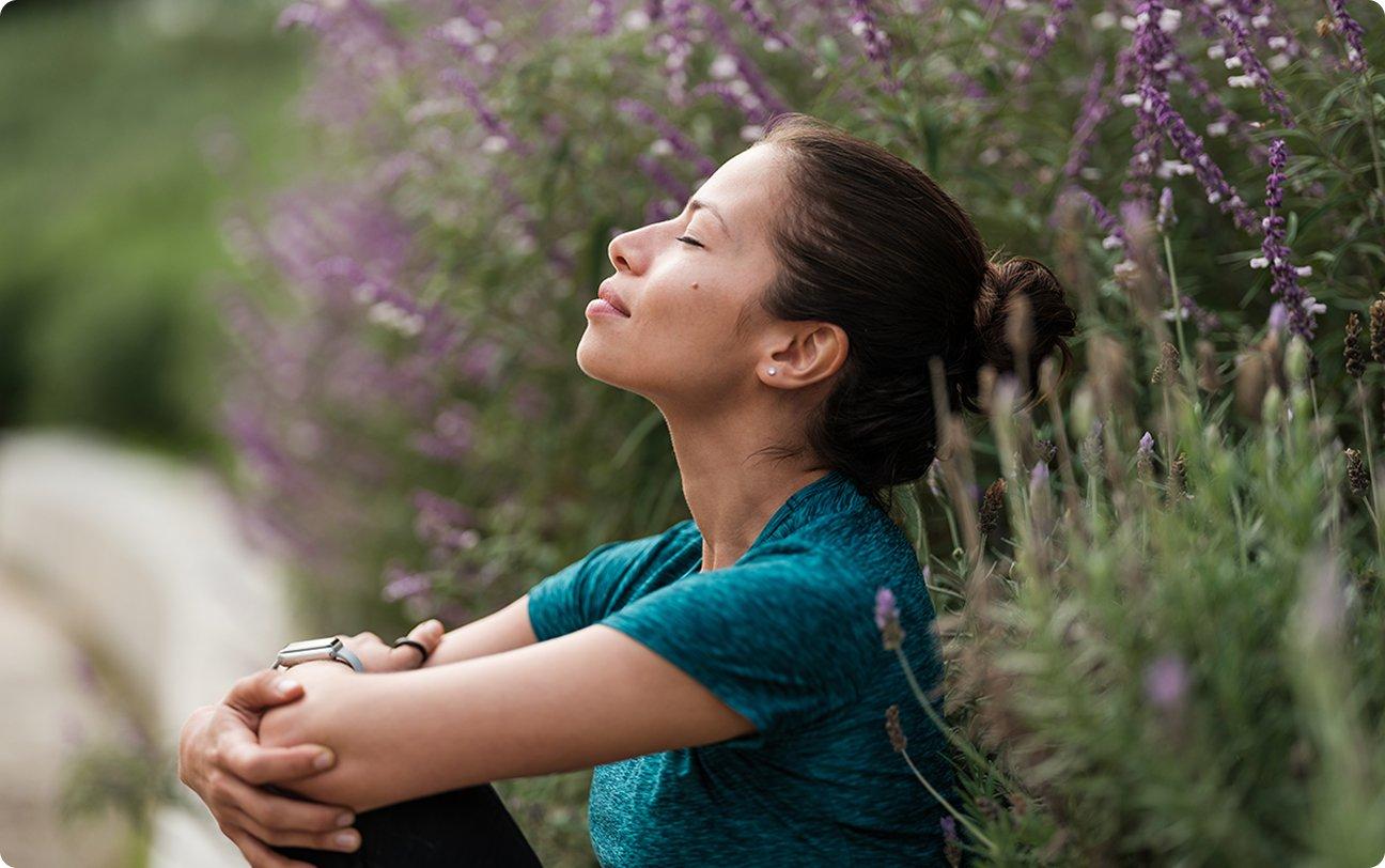 Woman sitting down outside with her eyes closed