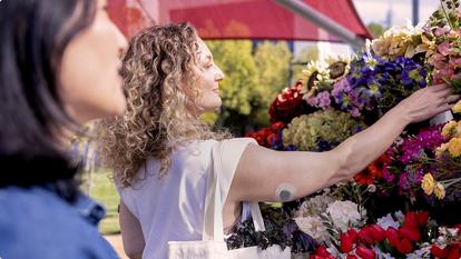 Woman picking out flowers in an outside shop while wearing the sensor