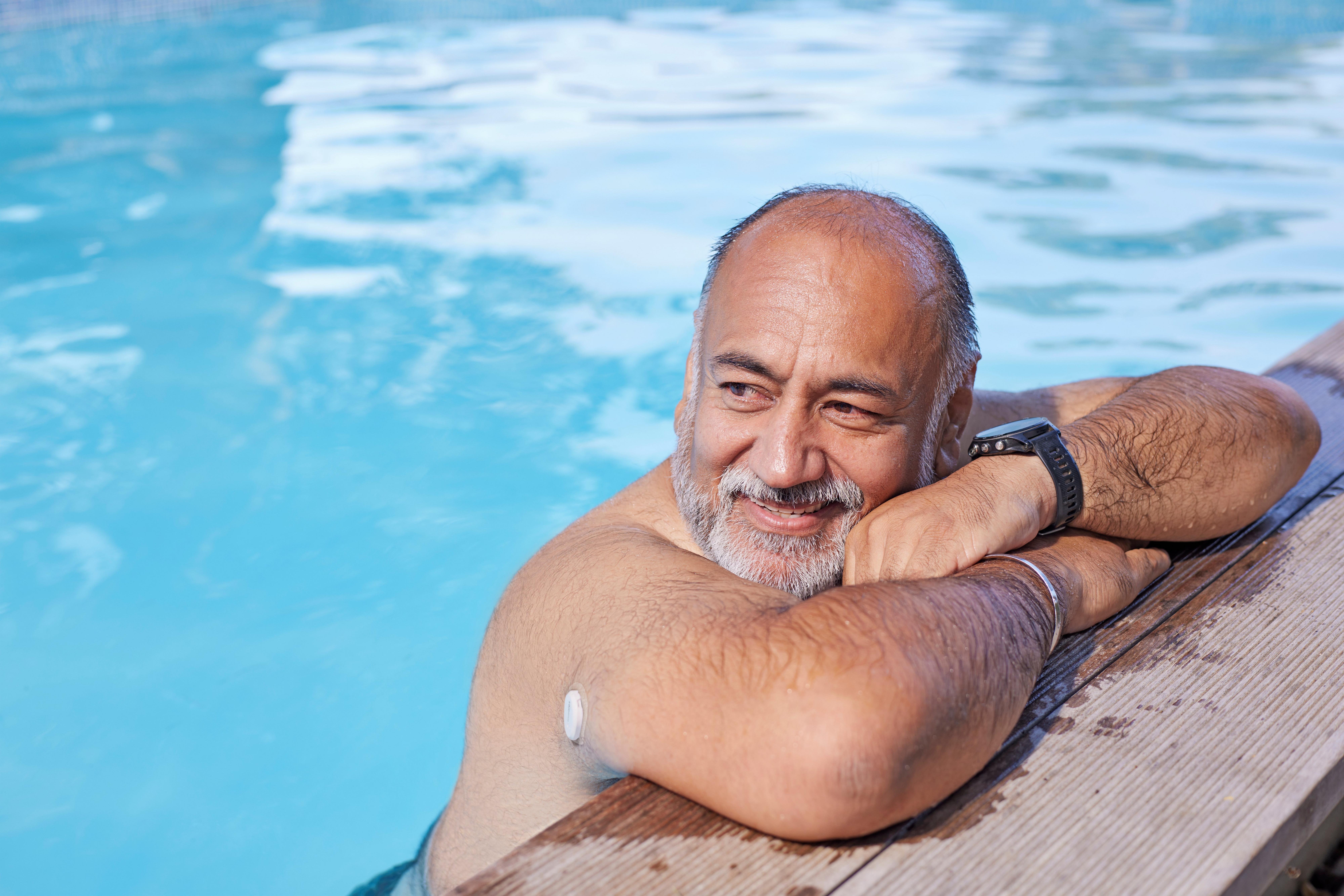 Man in swimming pool wearing Dexcom ONE+ device
