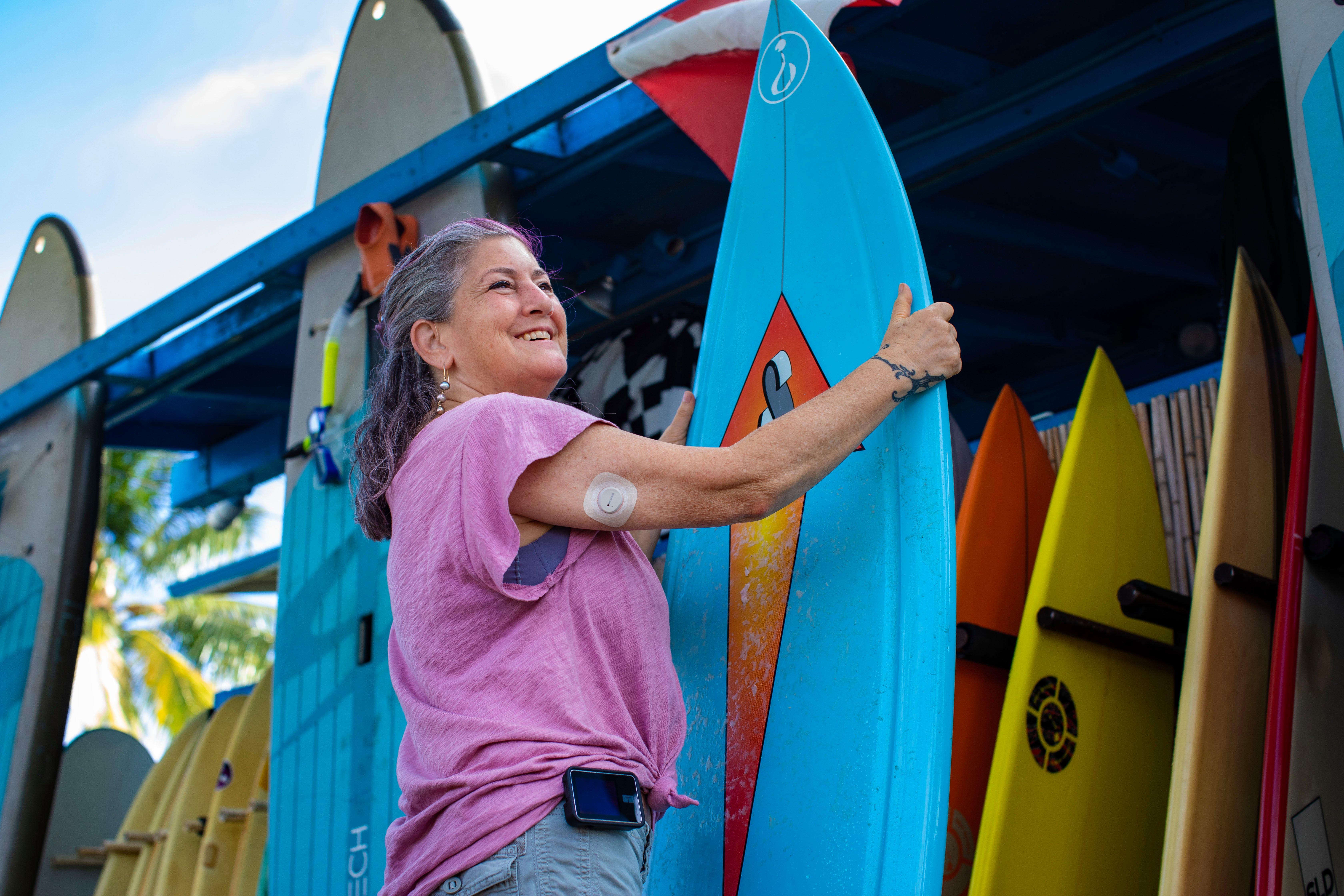 Woman wearing a Dexcom G7 CGM while storing a surfboard