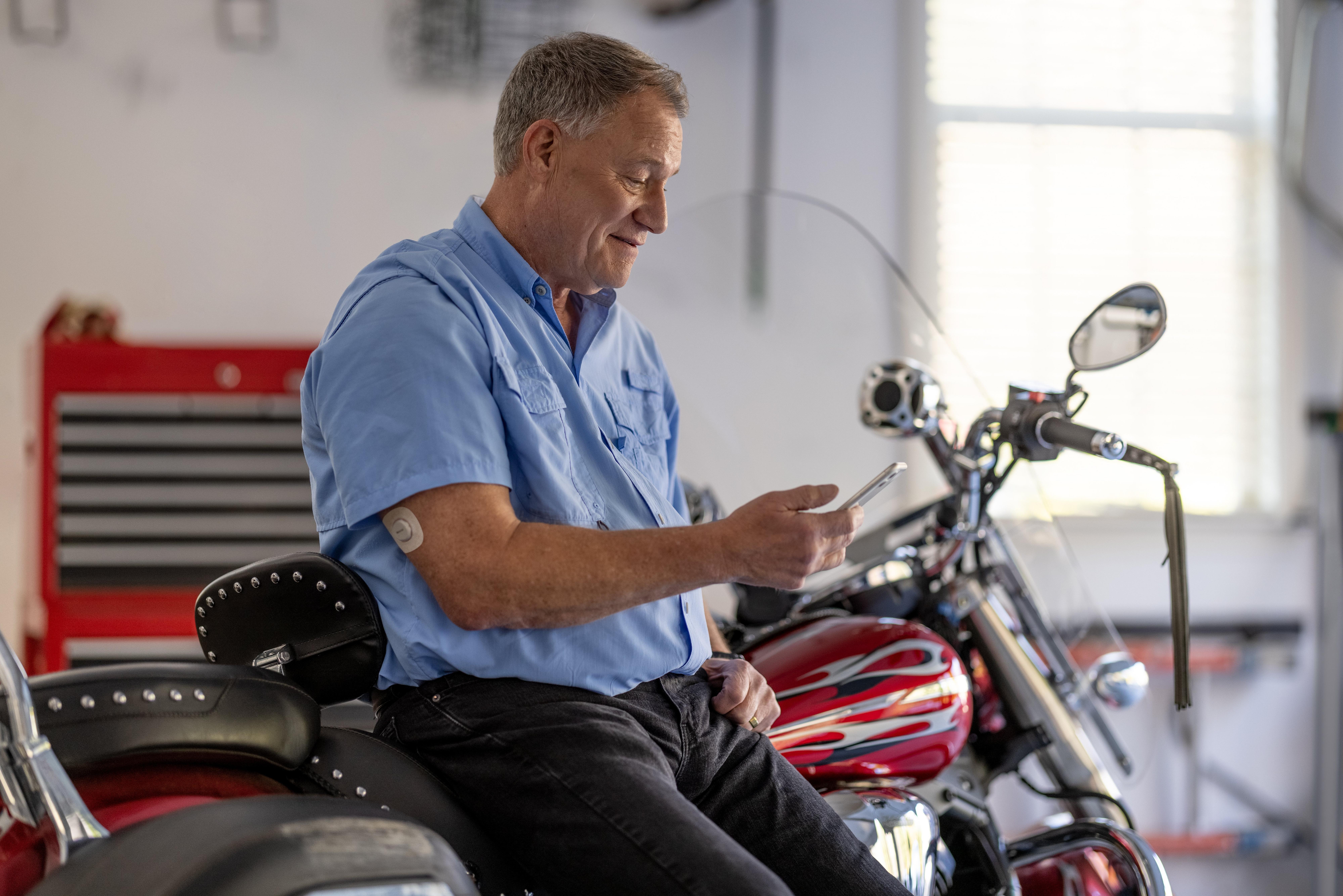 man leaning against motorcycle checking phone wearing g7 sensor