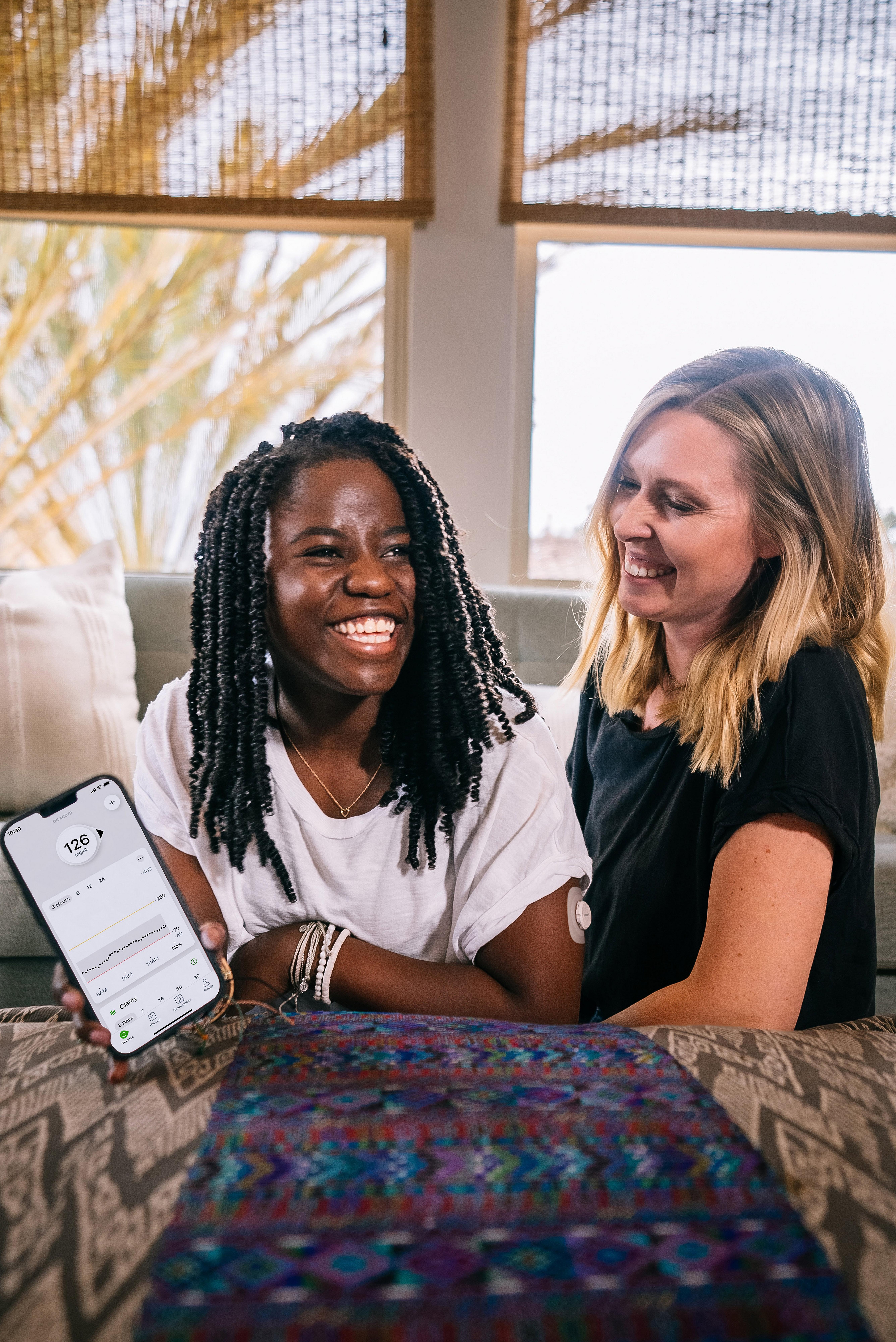 Keary and Zola smiling showing glucose readings on smart device using Dexcom G7 CGM app