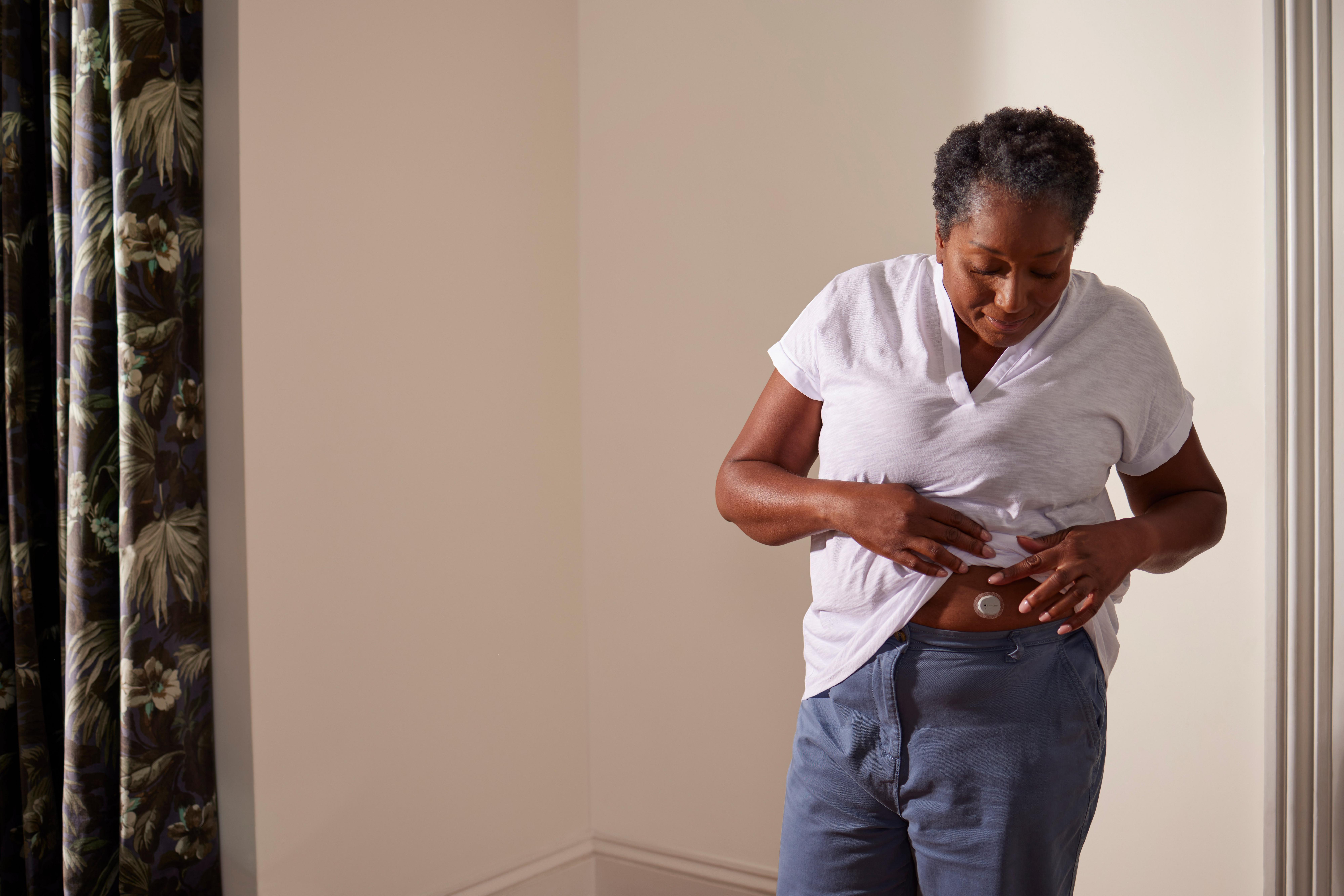 Vrouw controleert Dexcom ONE+ sensor op haar buik