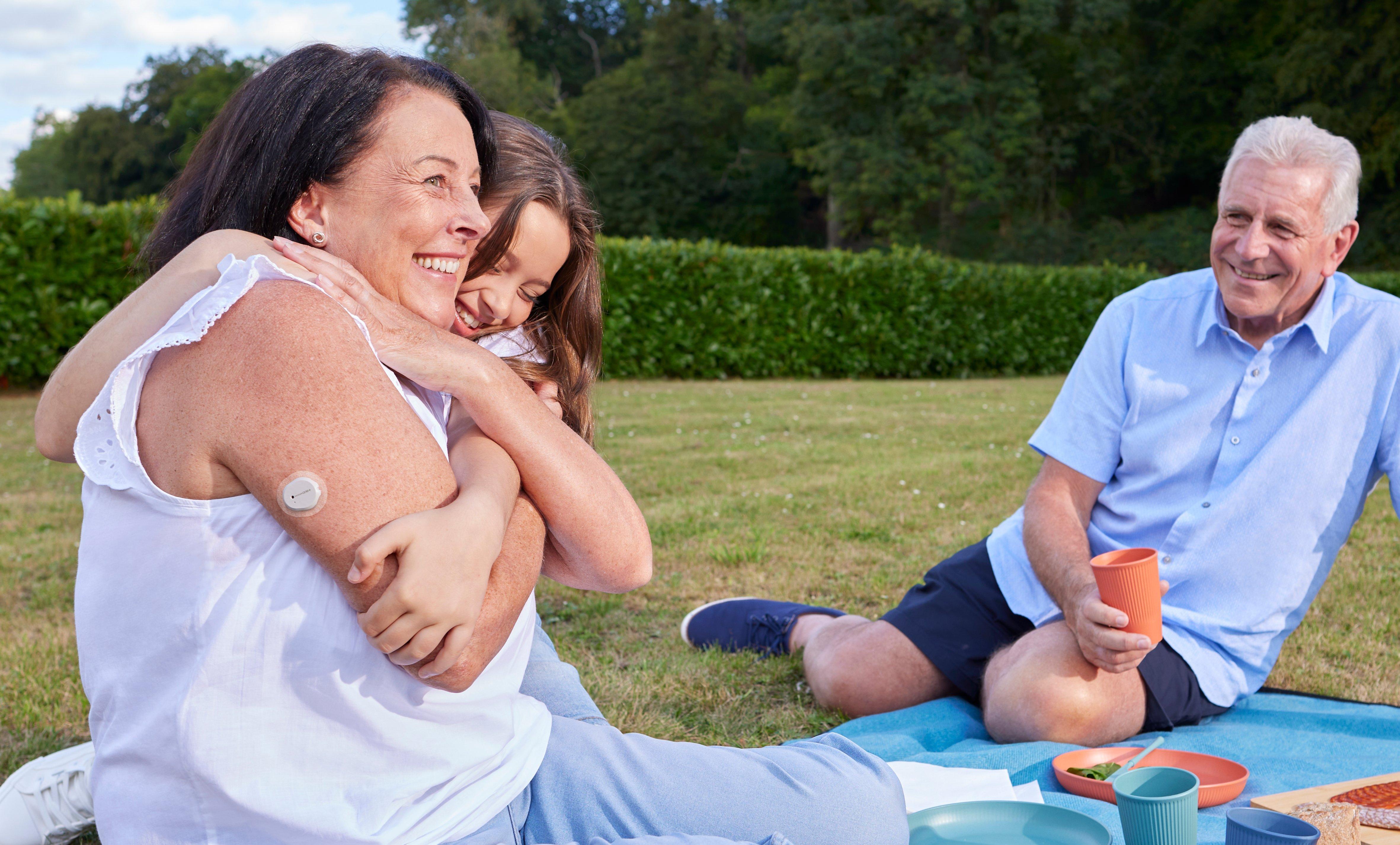 Giovane ragazza che abbraccia una donna anziana con un sensore Dexcom ONE+ sulla parte superiore del braccio