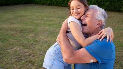 Starszy mężczyzna z czujnikiem Dexcom ONE+ na ramieniu, uśmiechający się i przytulający wnuka