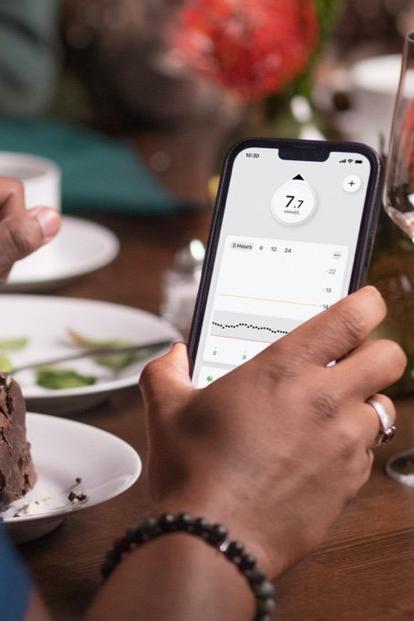 A man checks his Dexcom G7 app at dinner