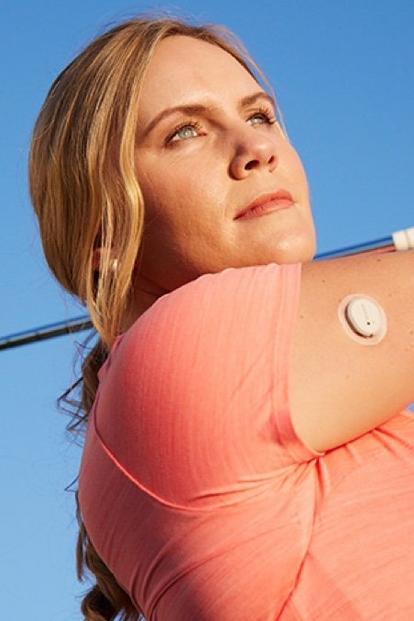 A woman wearing a Dexcom G7 sensor plays golf