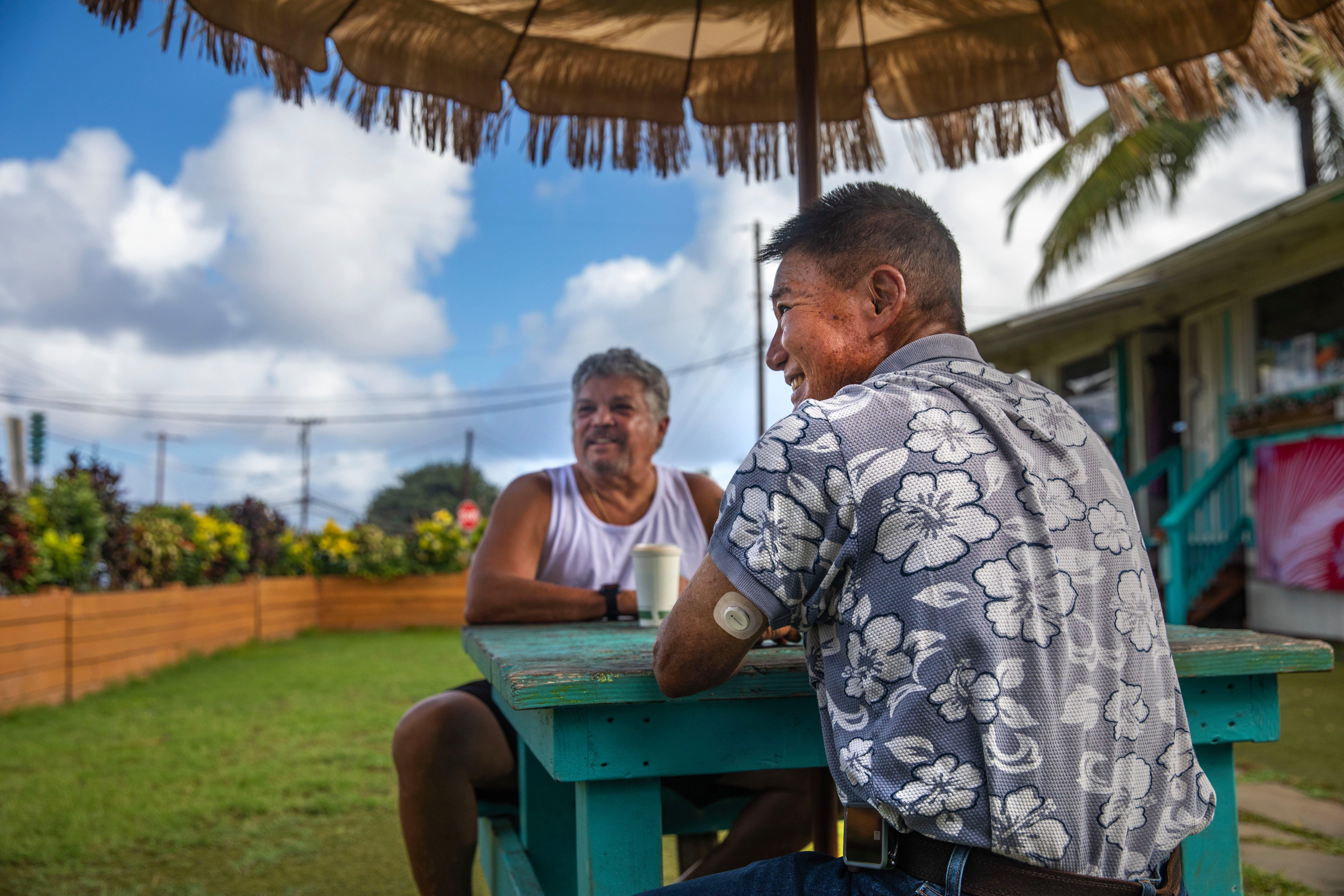Man wearing Dexcom G7 CGM sensor on arm and sitting with friend outdoors