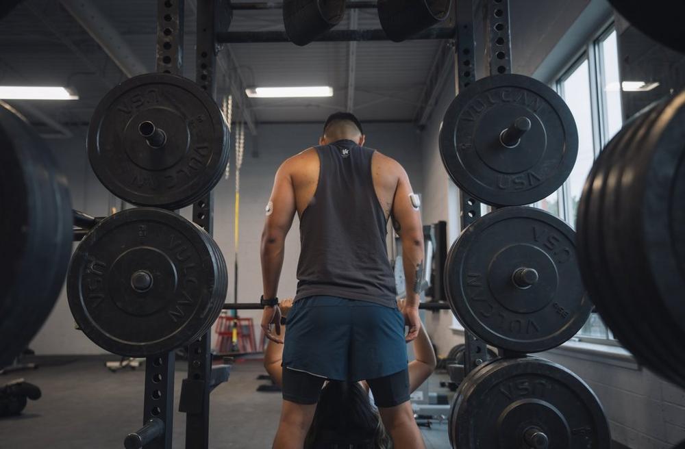 Man lifting weights in the gym, wearing Dexcom CGM sensor on the back of his arm