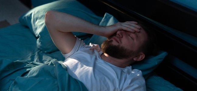 Man in bed with his hand on his face