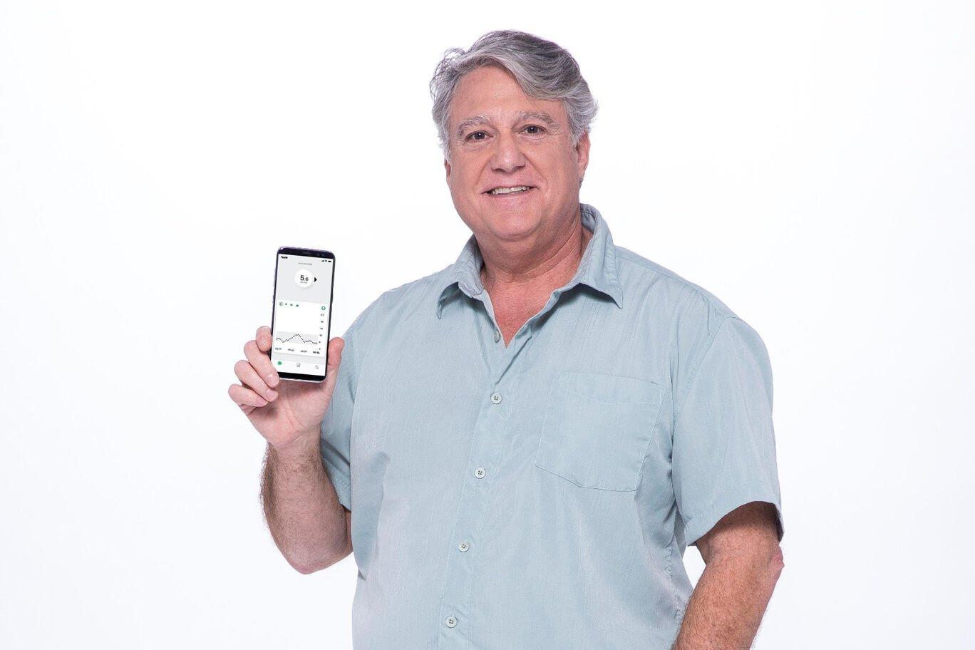 Bărbat cu cămașă gri care susține telefonul mobil