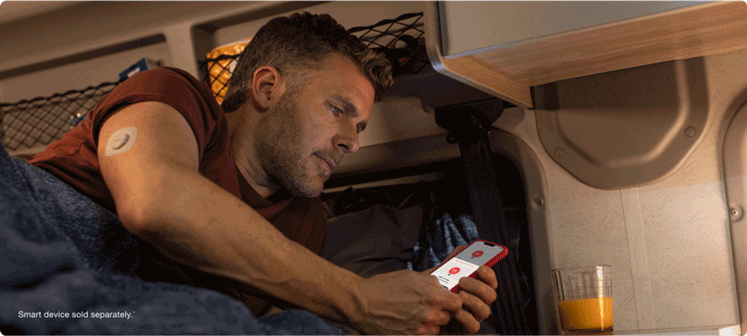 Dexcom user checking glucose levels in bed, smart devices sold separately