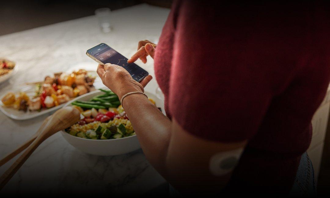 Woman in kitchen preparing a meal while viewing Stelo app insights