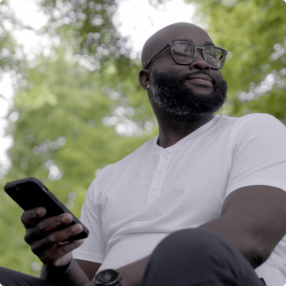 Man outside in nature looking up and away from his phone