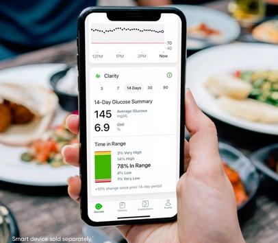 Smartphone with Clarity app and glucose readings at dinner table
