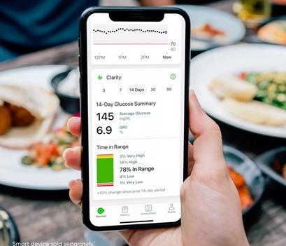 Smartphone with Clarity app and glucose readings at dinner table