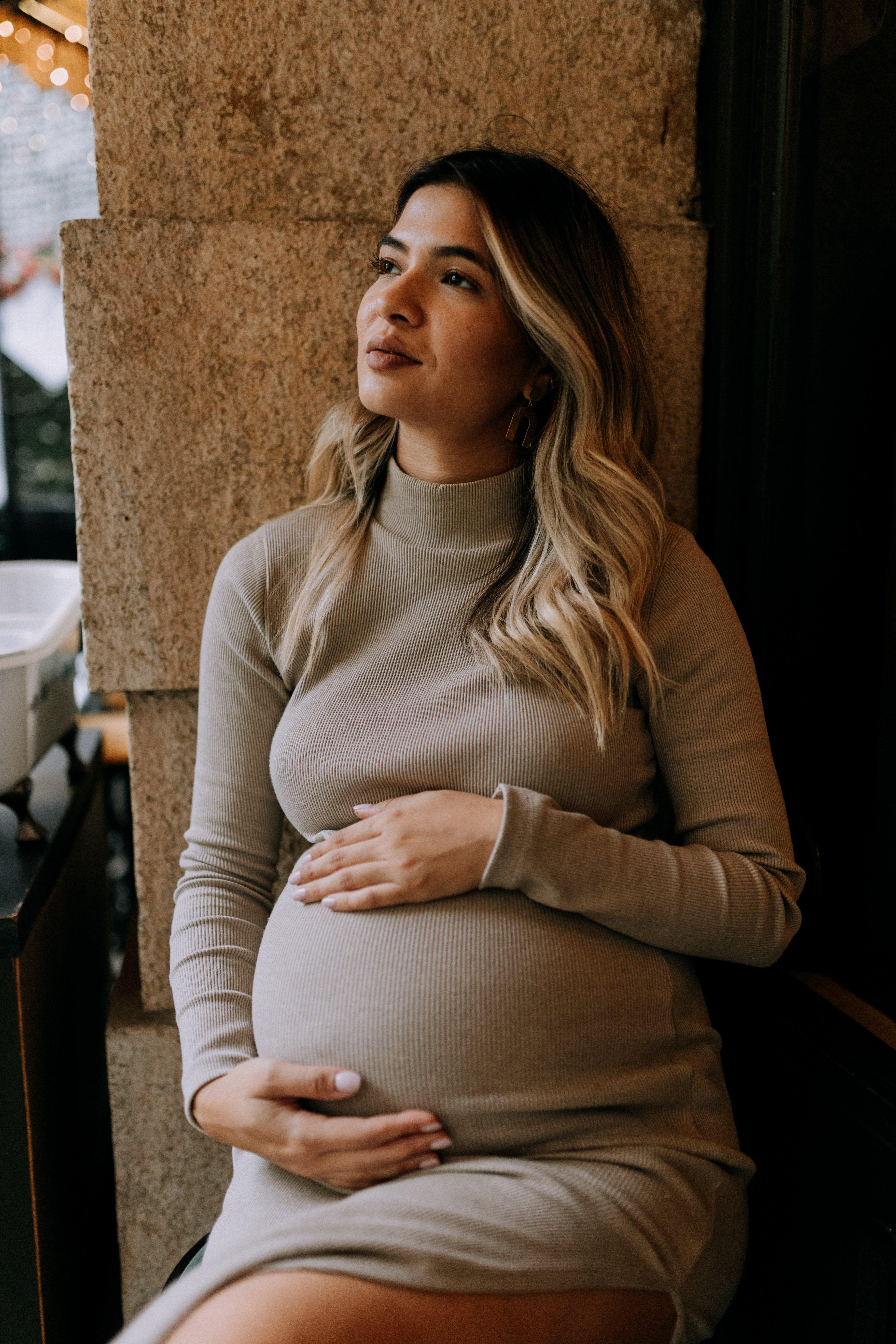 Sitting pregnant woman holding her belly