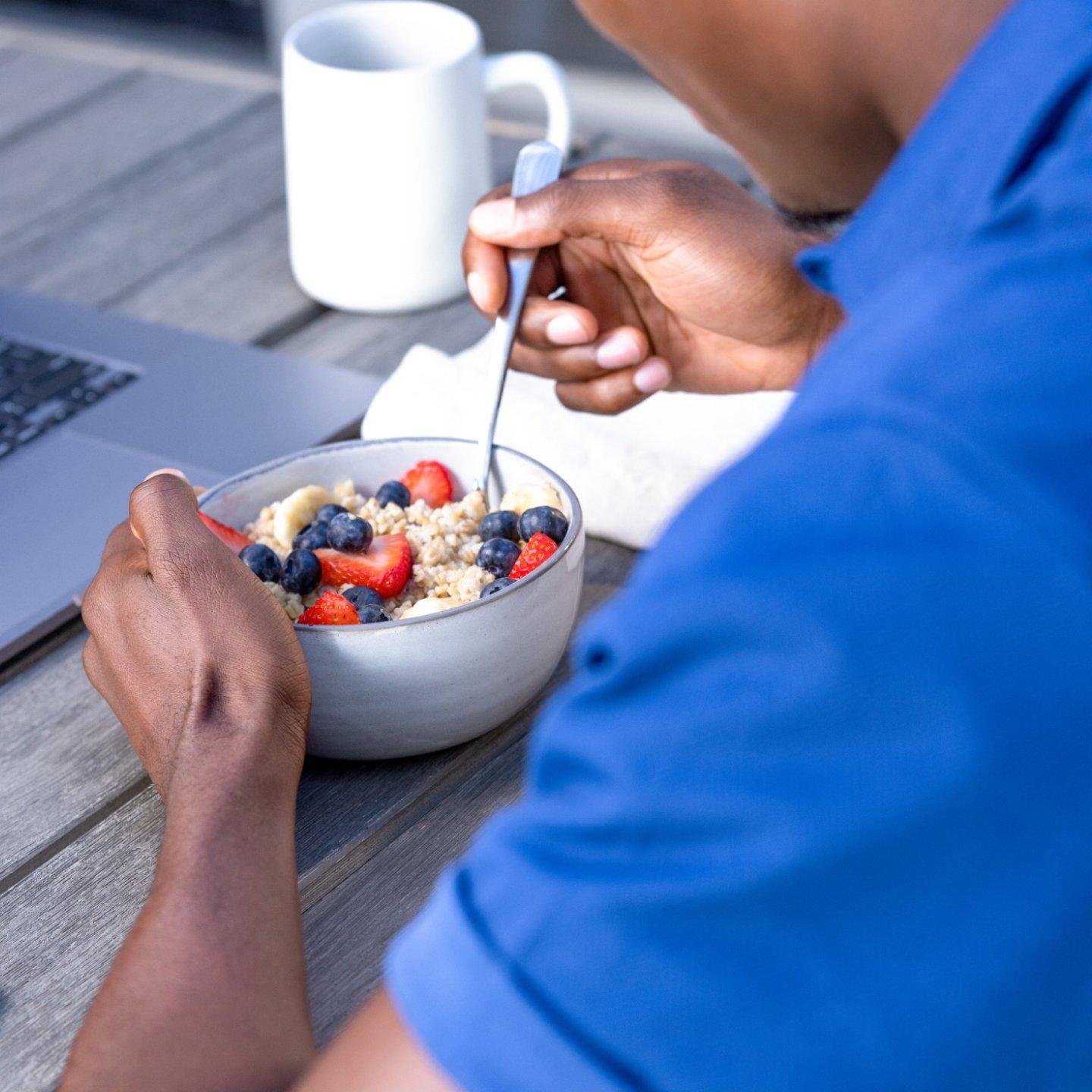 man eating bowl of oatmeal and fruit