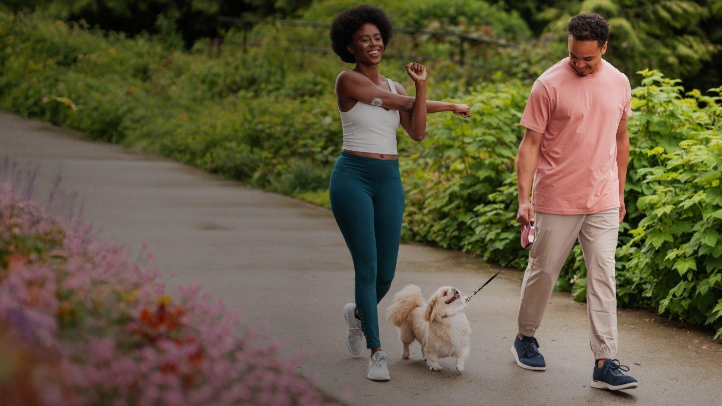 man and woman wearing stelo biosensor while walking dog