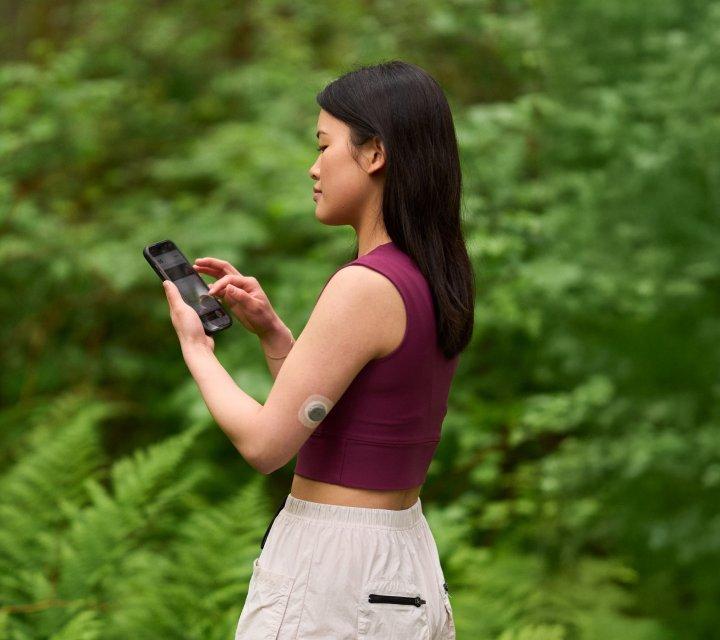 Woman wearing stelo biosensor looking at her phone