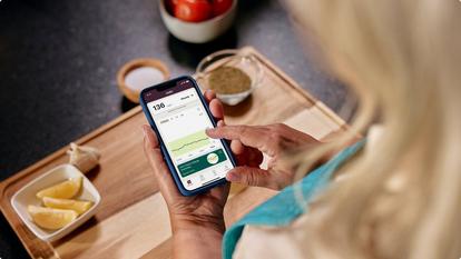 Woman checking Stelo app in kitchen