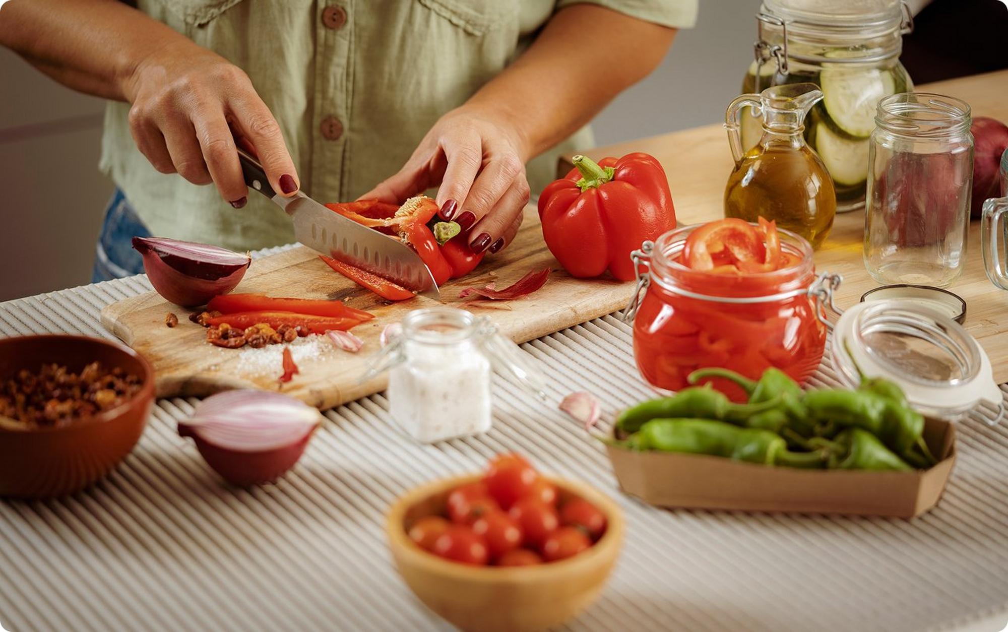 person cutting red bell peppers