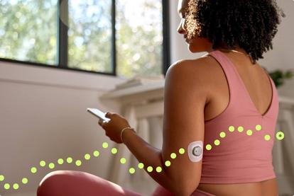 Woman wearing workout clothes while looking at her phone and wearing the Stelo sensor.