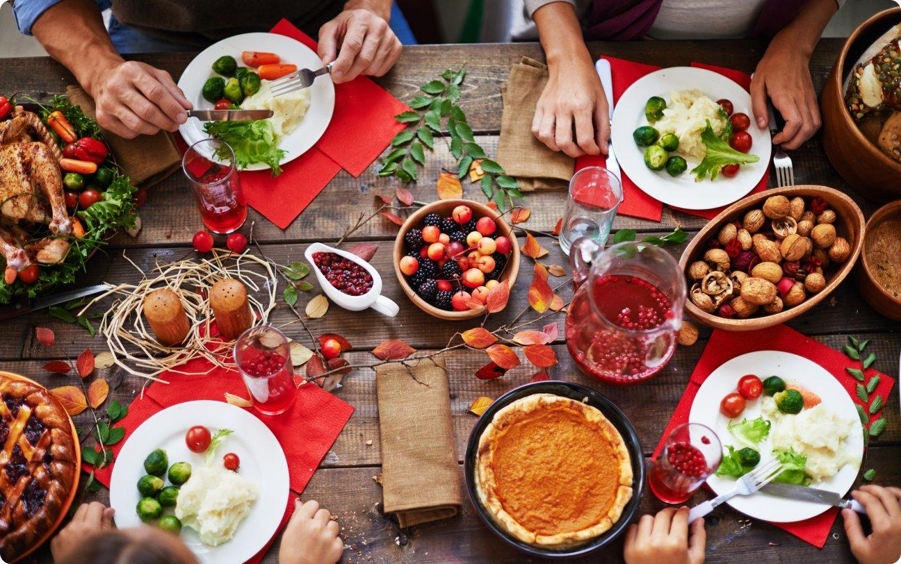 huge buffet of festive food on table with several people eating on it.