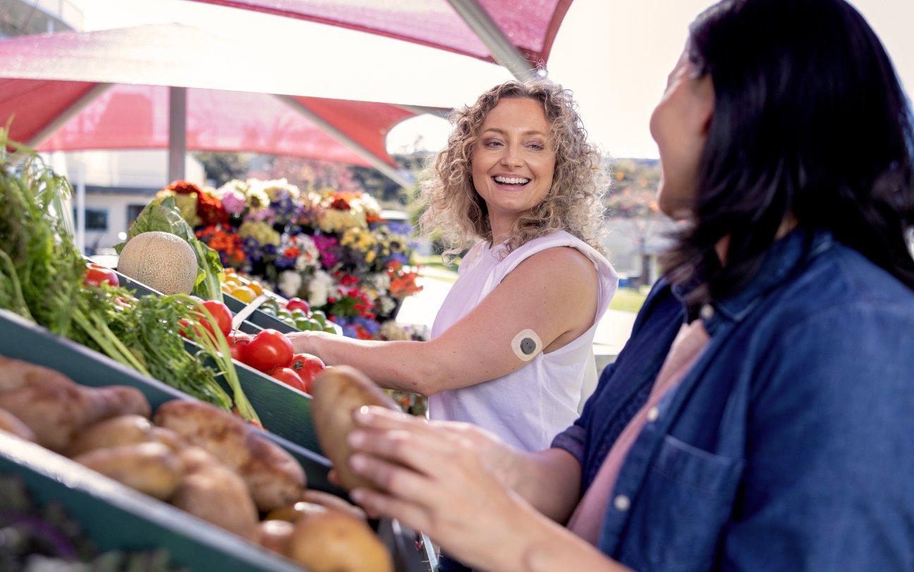 Stelo biosensor is FSA and HSA eligible. Woman wearing Stelo talking to a friend.