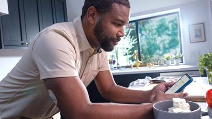Man in kitchen checking Stelo app on smartphone