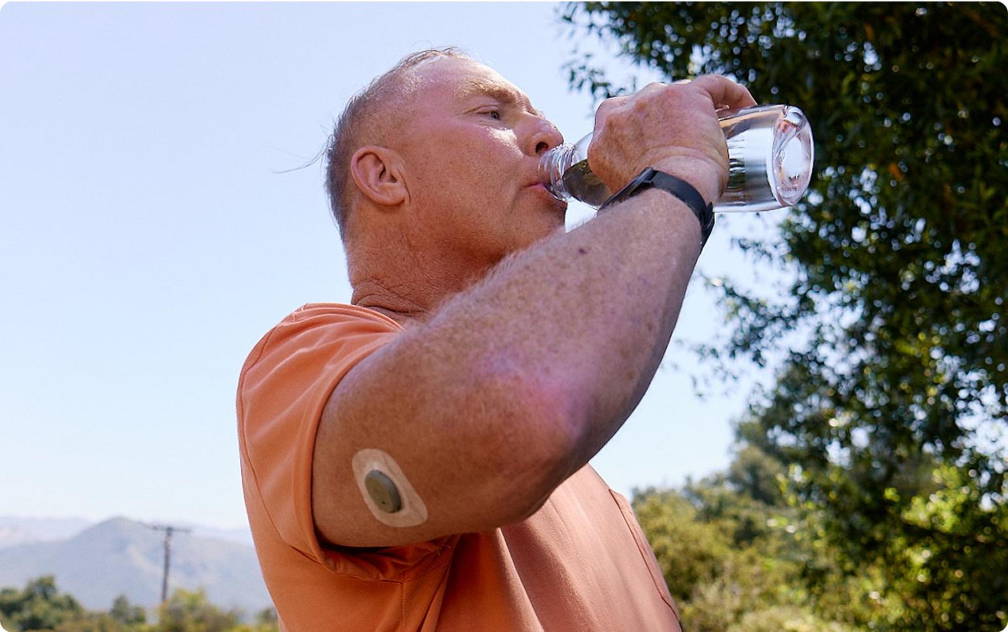 man wearing stelo biosensor drinking water