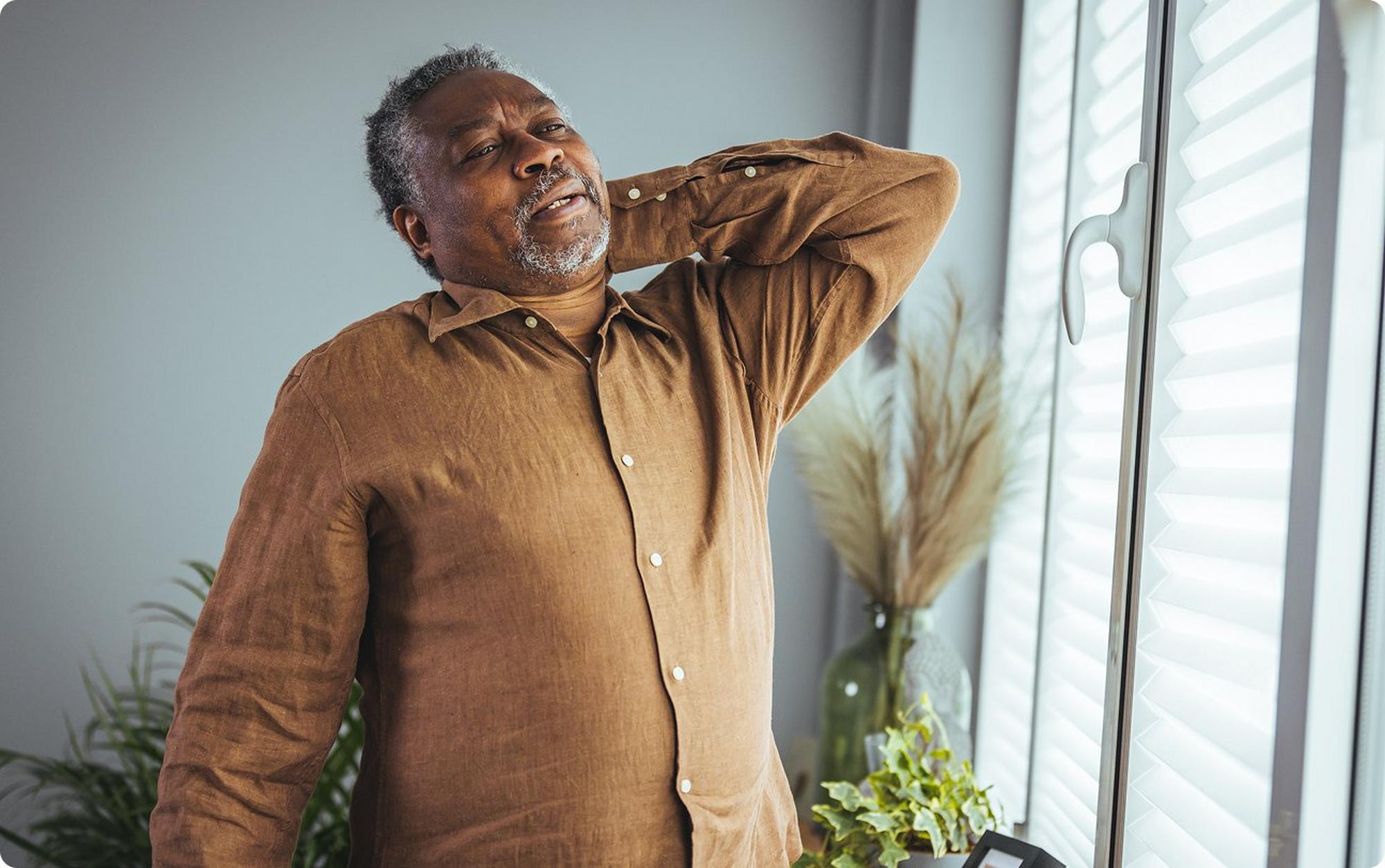 senior man stretching back in living room