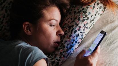 Woman in bed awake on phone
